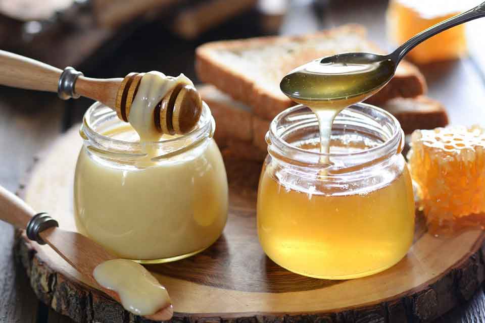 Set honey vs runny honey side by side – creamy soft-set honey in a jar with honey dipper next to clear golden runny honey being poured from a spoon