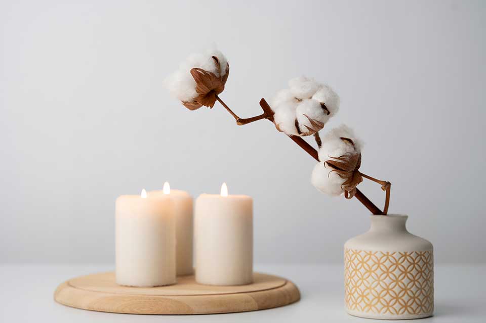 Three white paraffin pillar candles burning on a wooden tray – typical artificial paraffin candles often used in home décor